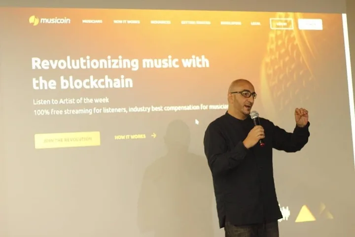 Skillz presenting, Musicoin on screen behind him